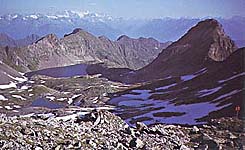 Il Lago Pìcol con a destra la caratteristica foggia del Castel di Pìcol. Sullo sfondo il Gruppo Bernina